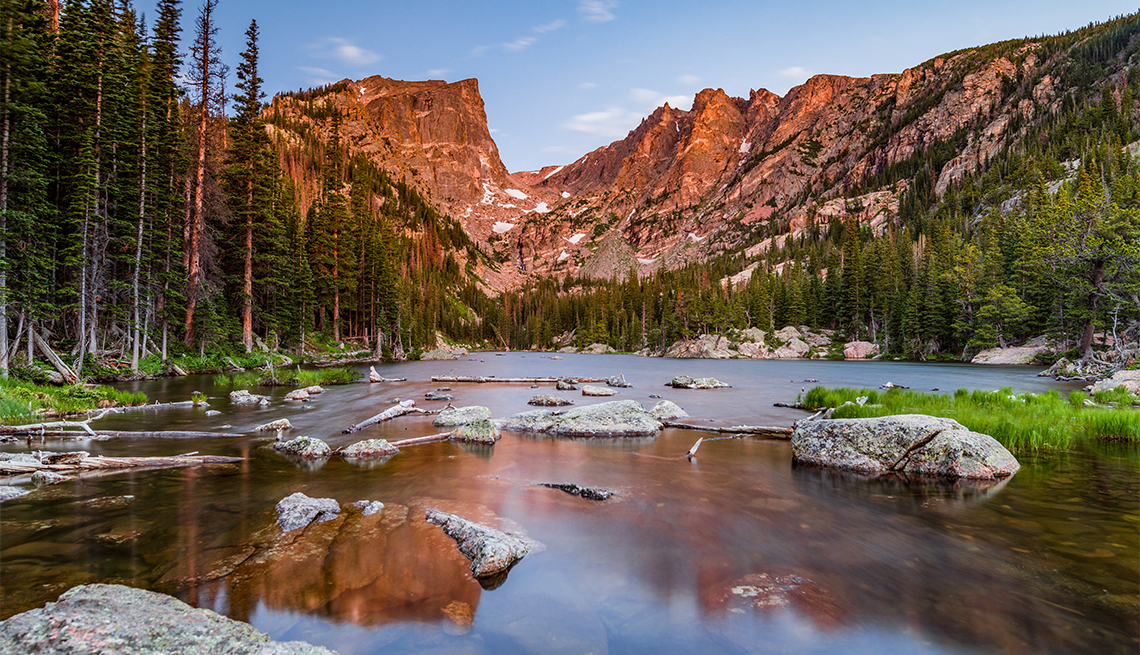 A scenic landscape photograph of Dream Lake in Rocky Mountain National Park, Colorado, with mountains and trees reflected in the water.
