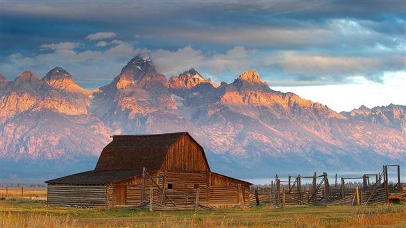 Sunset over Grand Teton National Park with old barn in foreground.