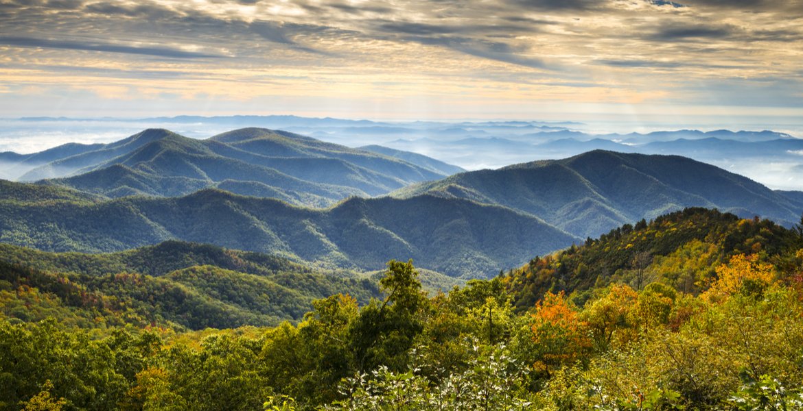 Rolling hills of the Blue Ridge Mountains covered in a light blue atmospheric haze under a cloudy sky.