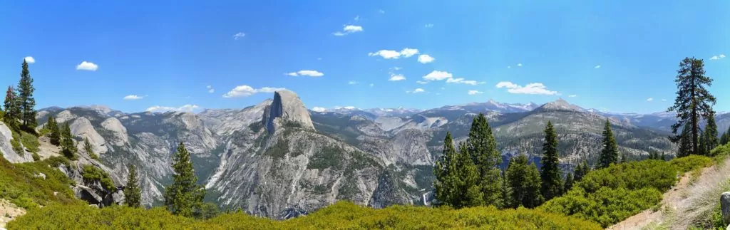 Yosemite National Park Panoramic view of Yosemite National Park. Rocky and green mountains surrounded by a blue sky.